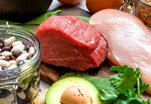 Brand food photo: a jar of dried beans, raw beef, raw chicken breast, half an avocado and parsley