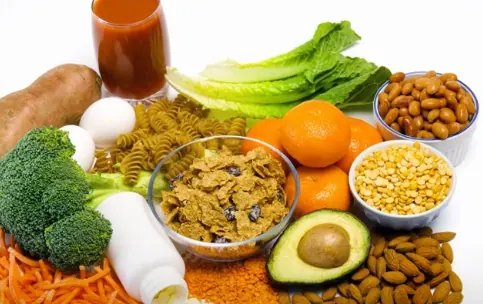 Broccoli, carrots, nuts, oats and other whole foods spread across a table