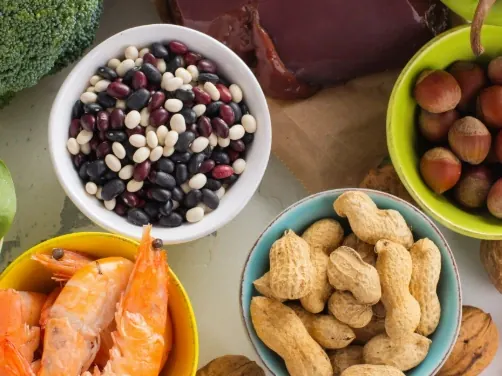 Brand food photo: bowls of mixed beans, peanuts in the shell, hazelnuts and shrimp, with broccoli at the edge