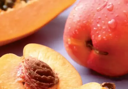 Brand food photo of a whole nectarine beside halved peaches and papaya